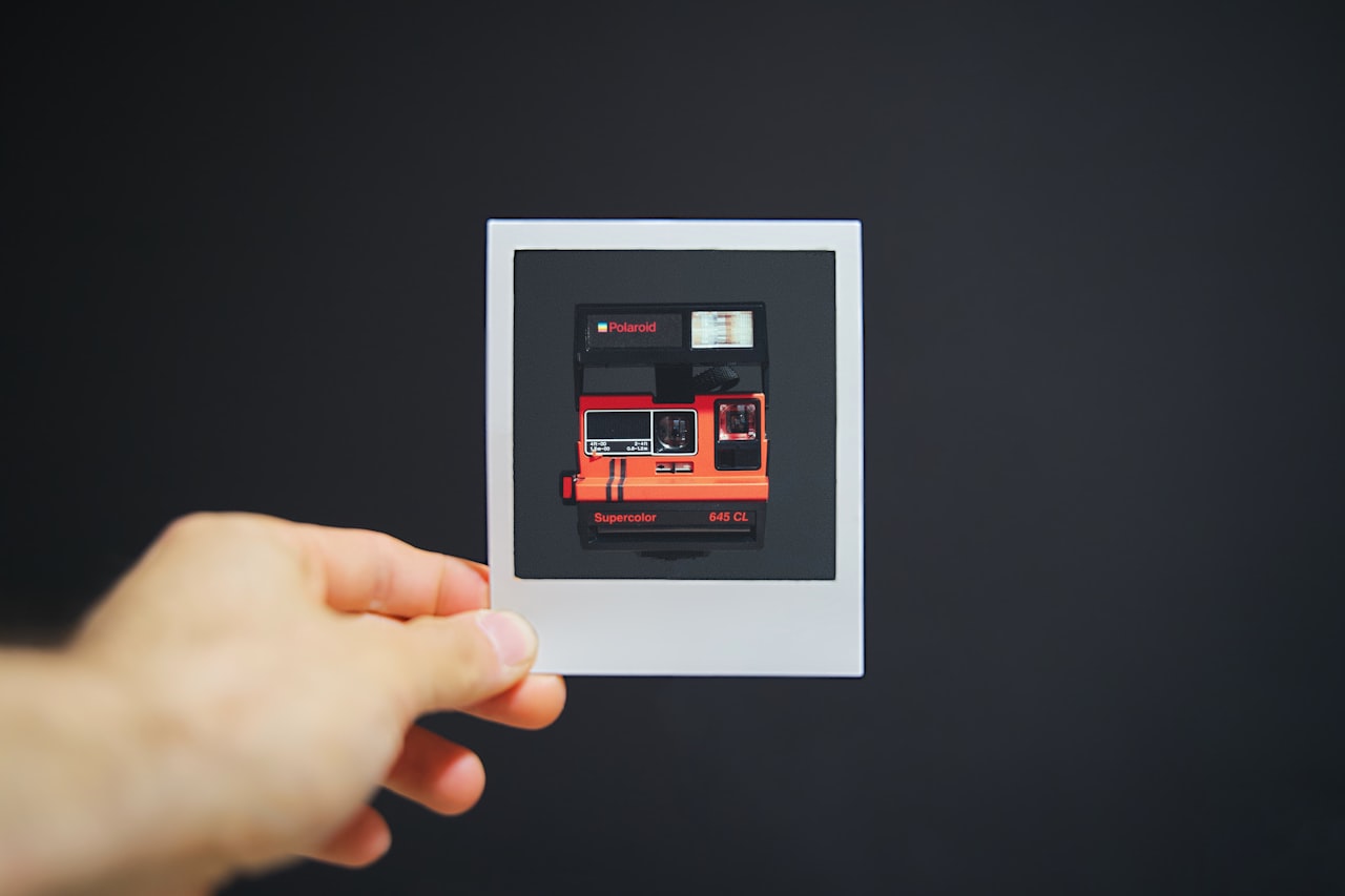 Ruka koja drži manju fotografiju polaroidnog fotoaparata
